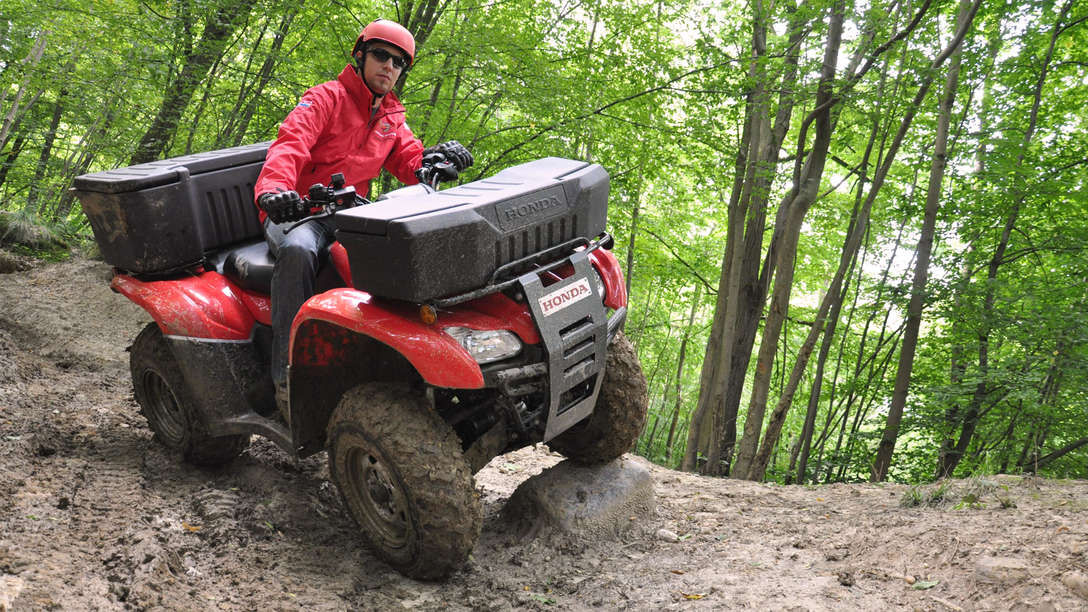 Front three-quarter, right facing Fourtrax 420, being used by model, forest location.