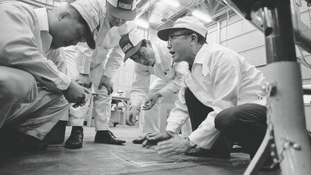 Soichiro Honda and some factory workers in white overalls.
