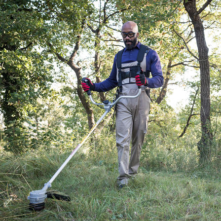 Model using Honda cordless brush cutter in garden location.