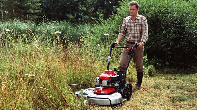 Front 3/4 left facing Grass Cutter being used by model. Garden location.