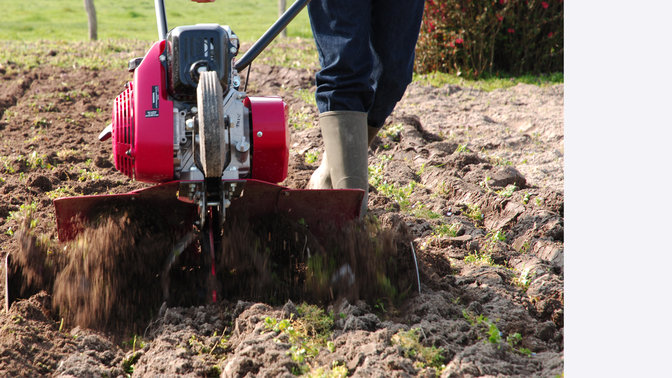 Compact tiller, garden location, close up.