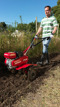 Compact tiller, being used by model, garden location.