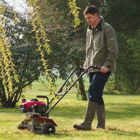 Honda microtiller, de-thatching attachment, being used by model, on location.