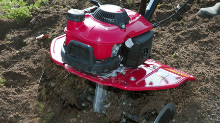Close up of mini tiller in use, garden location.