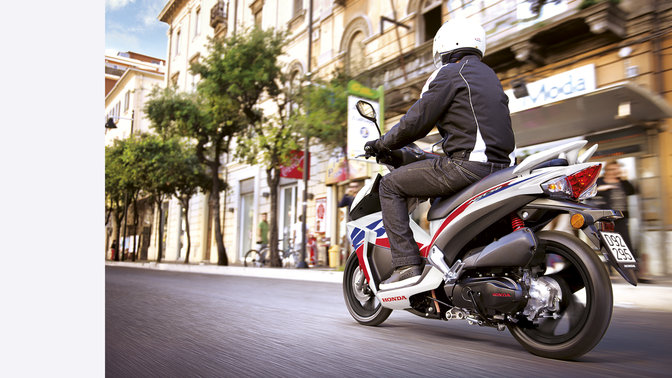 Rear 3-quarter view of nsc50r with rider.