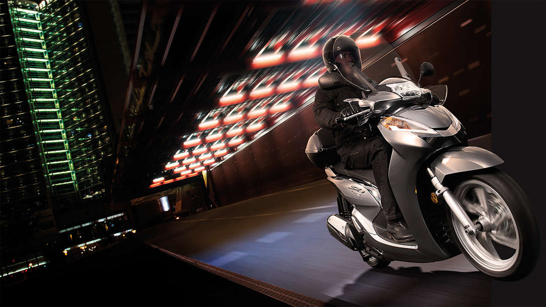 Sh300i being driven in the night down a quiet brightly lit street