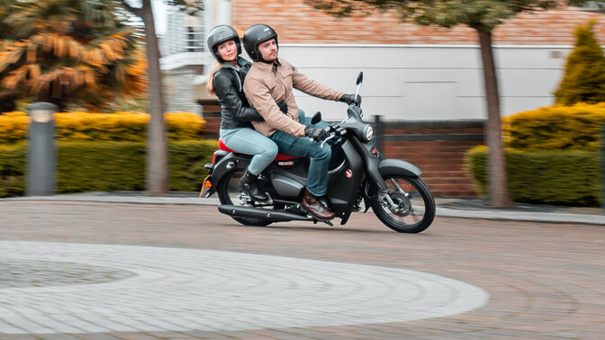 Honda Monkey on side stand in road with rider