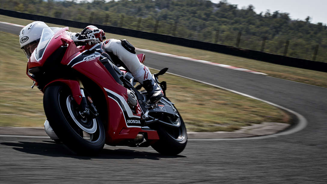 Front three-quarter facing Honda CBR100RR Fireblade with rider on race track.