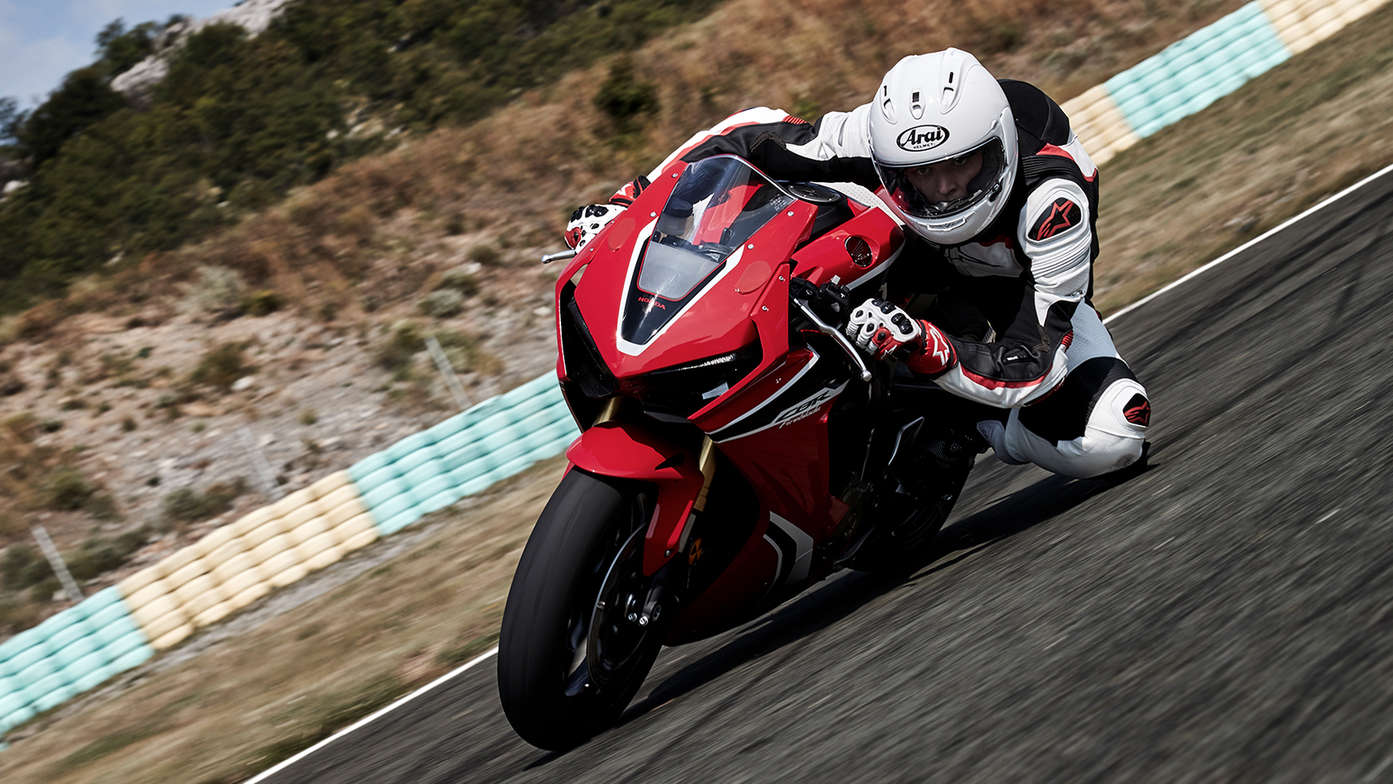 Front three-quarter facing Honda CBR1000RR with rider on track with knee down.