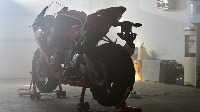 Rear three-quarter facing Honda CBR1000RR on stand in workshop.