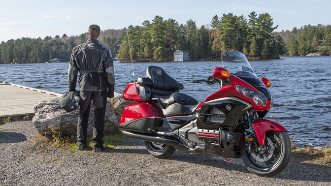 Gold Wing leaning into bend, left-facing with Rider, coastal location.